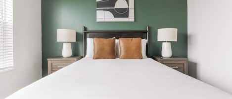 Une chambre d’hôtel comprenant un lit, deux tables de chevet avec des lampes, une tête de lit et une œuvre d’art murale.