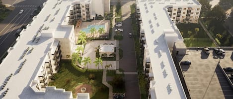 A modern hotel complex with multiple buildings, a central courtyard with a pool, and a parking area.