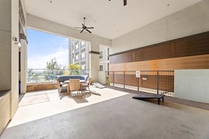 Ein Balkon mit Tisch und Stühlen, einem Deckenventilator und Blick auf ein Gebäude im Hintergrund.