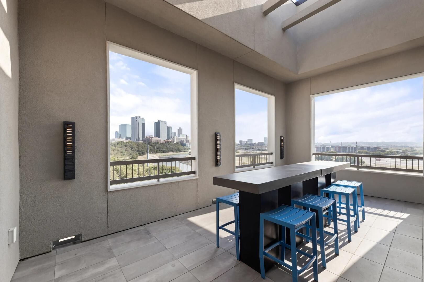 A balcony with a city view, a bar area with stools, and a large window.