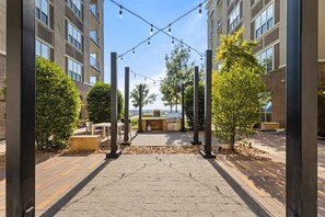 An outdoor patio area with a barbecue grill, seating, and string lights. - Landing | Amazing 2BD, Rooftop Lounge, Clubhouse (Fort Worth)