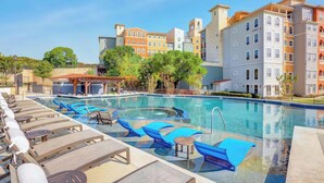 A swimming pool with lounge chairs and a pergola, surrounded by multi-story buildings. - Landing | Chic 1BD, Courtyard, Gym (San Antonio)