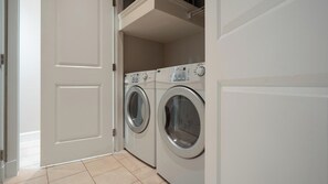 A laundry room with two front-loading washing machines and a white door. - Landing | Stylish 1BD, Gym, Courtyard (San Antonio)