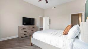 A bedroom with a bed, a dresser, a television, and a ceiling fan. - Landing | Stylish 1BD, Gym, Courtyard (San Antonio)