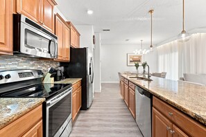 Eine moderne Küche mit Holzschränken, Edelstahlgeräten und einer Granitarbeitsplatte.