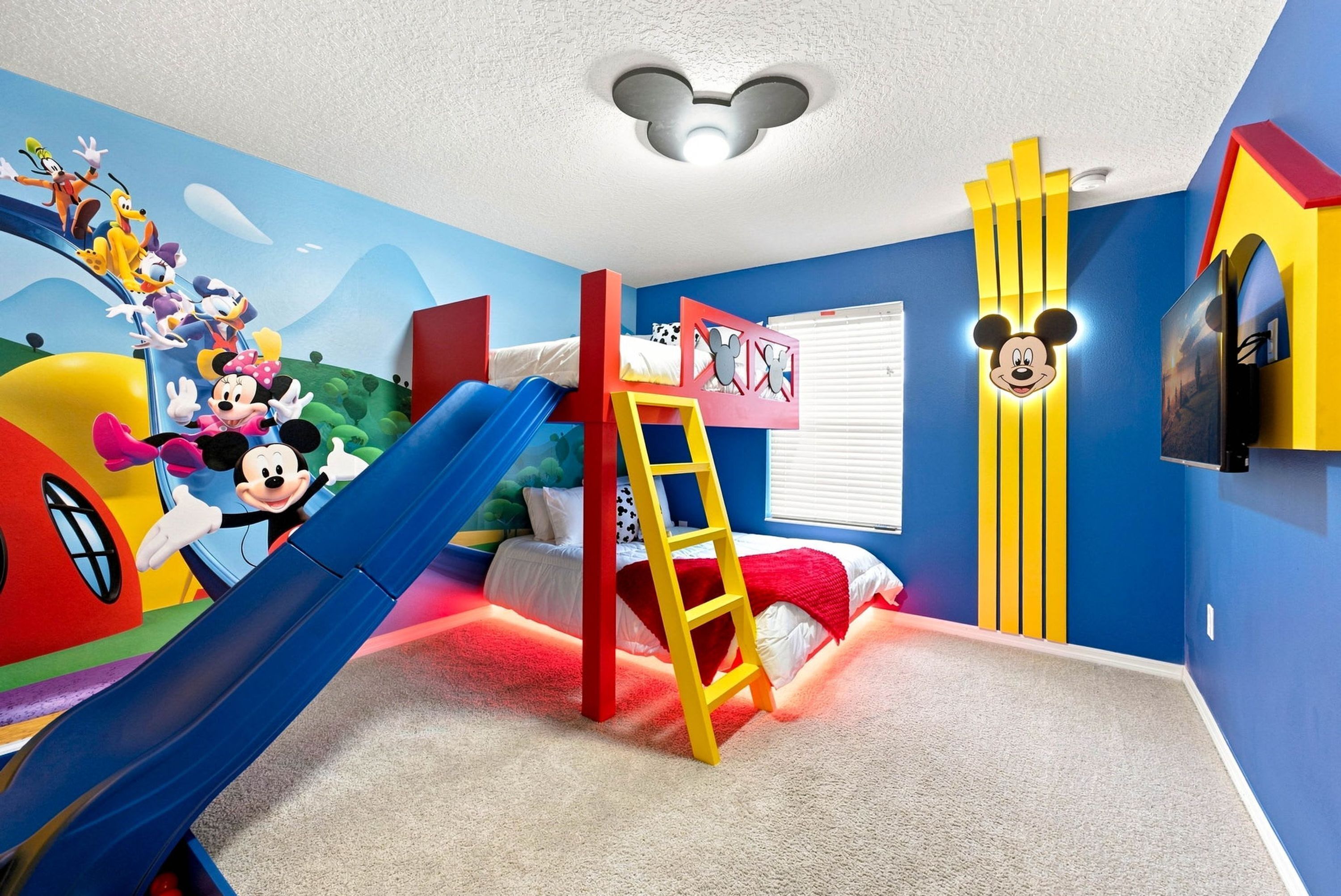 Een kinderkamer met een glijbaan, een ladder en Mickey Mouse decoraties.