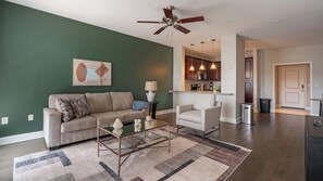 A living room with a sofa, armchair, coffee table, and a painting on the wall. - Landing | Stylish 1BD, Courtyard, Gym (San Antonio)