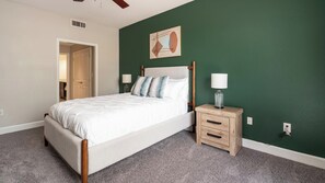 A bedroom with a bed, a nightstand, a lamp, and a door leading to another room. - Landing | Stylish 1BD, Courtyard, Gym (San Antonio)