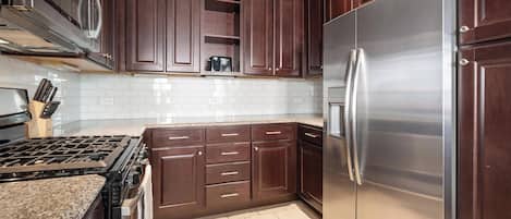 A kitchen with dark wooden cabinets, a stainless steel refrigerator, and a gas stove.