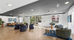 Eine moderne Lobby mit Sitzgelegenheit, einem Couchtisch und einer Zimmerpflanze.