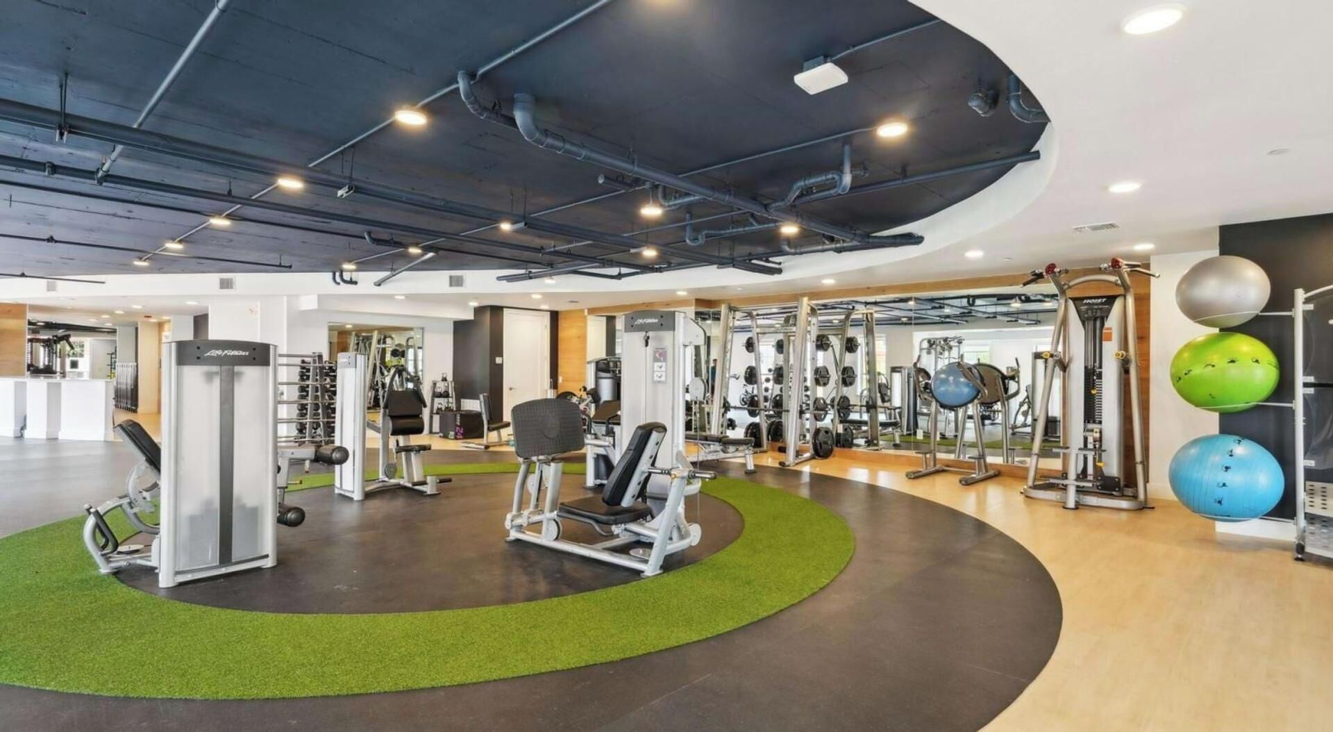 Ein modernes Fitnessstudio mit verschiedenen Trainingsgeräten, darunter Kraftgeräte und Kurzhanteln.