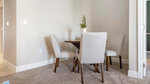 A small dining area with a round table and four chairs, a potted plant, and a door leading to another room. - Landing | Modern 2BD, Gym, Courtyard (San Antonio)