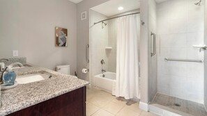 A bathroom with a granite countertop, a toilet, a bathtub, and a shower area. - Landing | Modern 2BD, Gym, Courtyard (San Antonio)