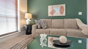 A living room with a sofa, a lamp, and a coffee table with decorative items. - Landing | Modern 2BD, Gym, Courtyard (San Antonio)