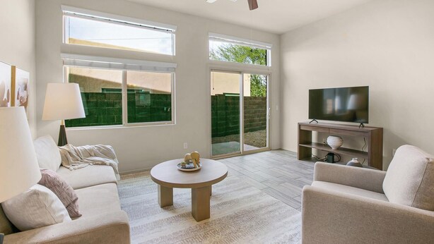A living room with a sofa, a coffee table, a TV on a stand, and large windows. - Landing | Stunning 1BD, Courtyard, Gym (San Antonio)