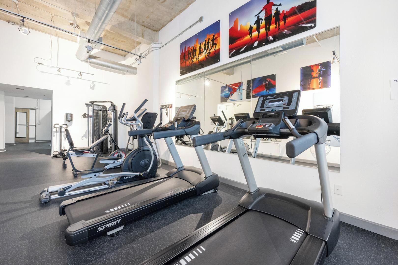 Une salle de sport équipée de tapis de course, de vélos elliptiques et d’appareils de musculation.