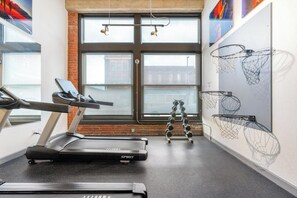 A gym with a treadmill, dumbbells, and a basketball hoop. - Landing | Incredible 1BD, Gym, Pool (Kansas City)