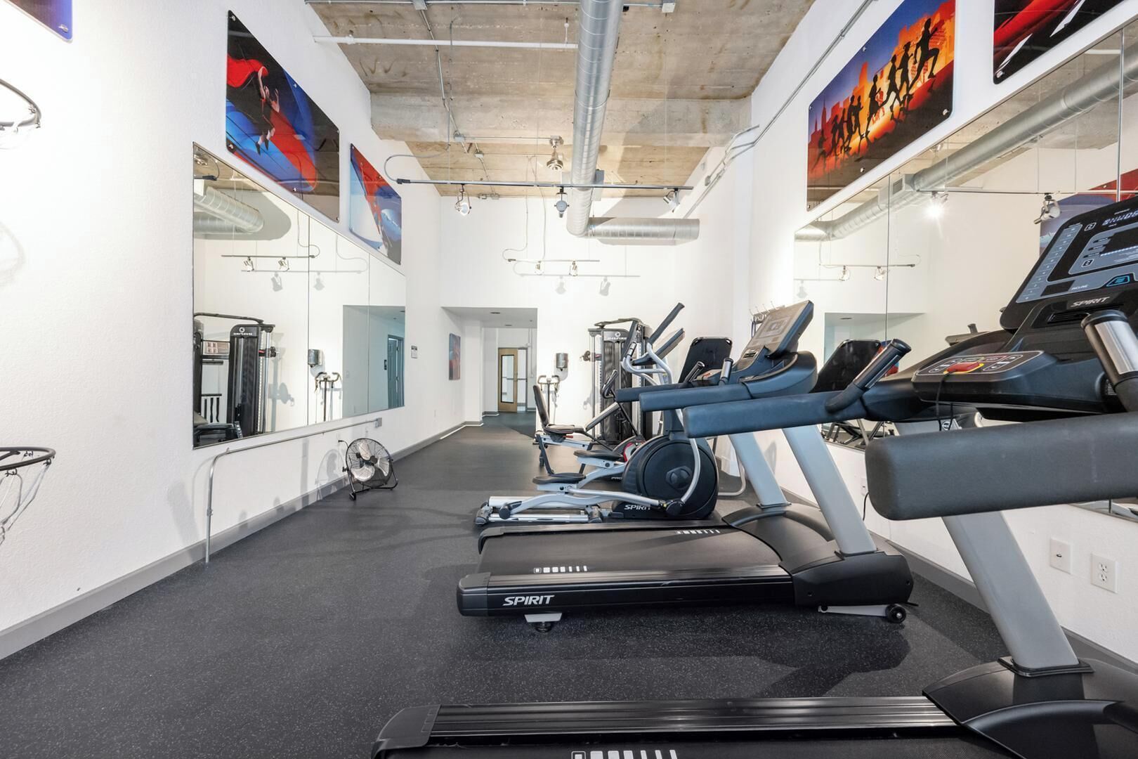 A gym with treadmills, exercise bikes, and mirrors on the walls.
