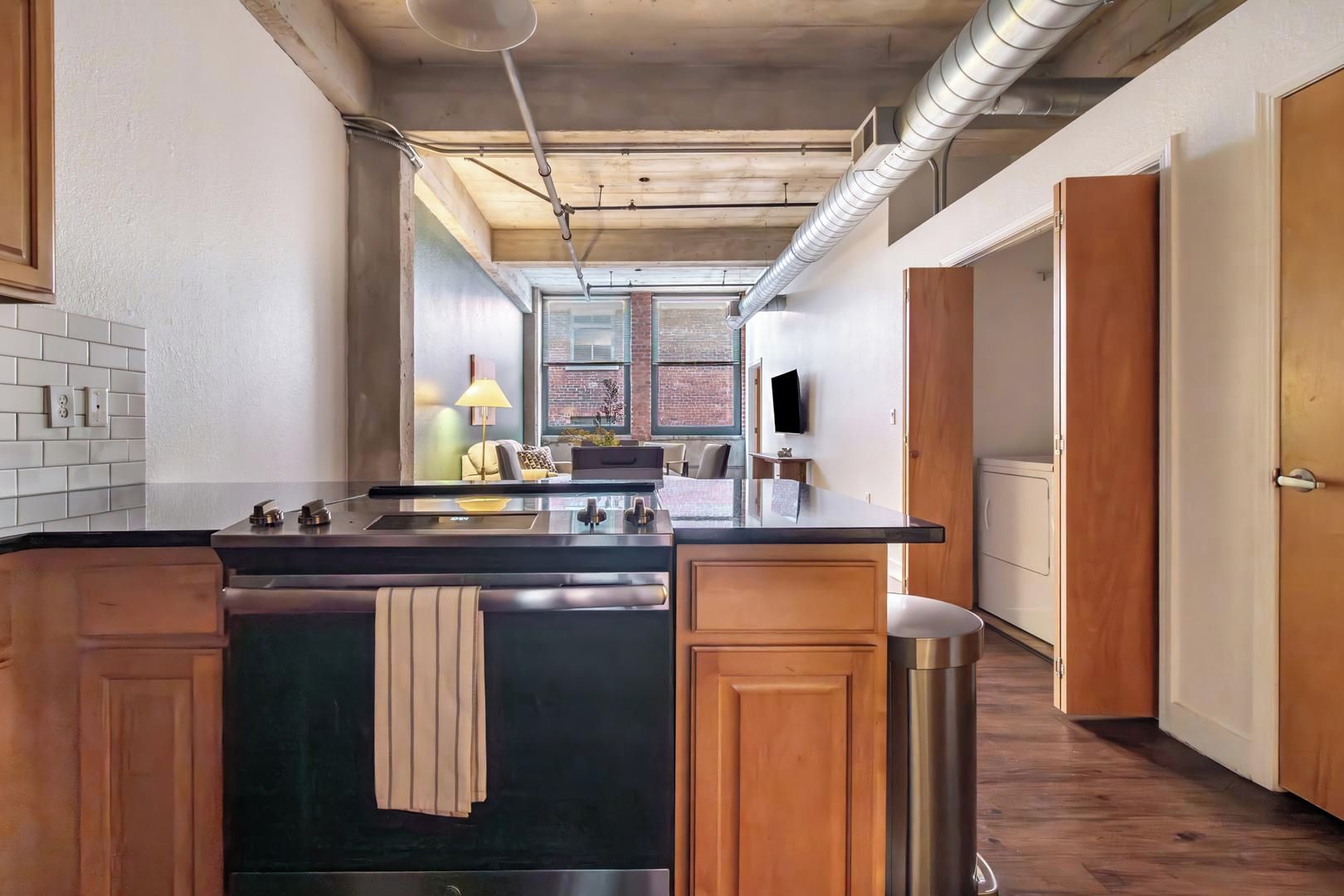 Une cuisine moderne dotée d’un îlot central, de meubles en bois et offrant une vue sur l’extérieur.