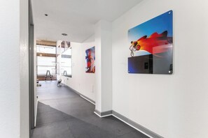 Ein Flur mit einer Treppe, die zu einem Fitnessbereich führt, einem an der Wand befestigten Kunstwerk und einem Türrahmen.