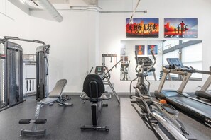 A gym with various exercise equipment including a treadmill, elliptical, and weight machines. - Landing | Chic 1BD, Pool, Gym (Kansas City)