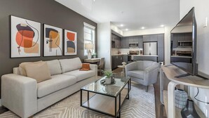 Una sala moderna con sofá, sillón, mesa de centro y arte abstracto en la pared.