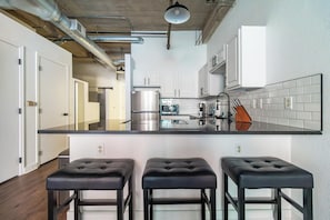 A modern kitchen with a central island, stainless steel appliances, and bar stools. - Landing | Stylish 1BD, Gym, Pool (Kansas City)