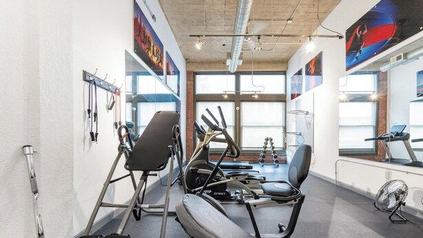 Un gimnasio con equipo de ejercicio, amplias ventanas y carteles motivacionales.
