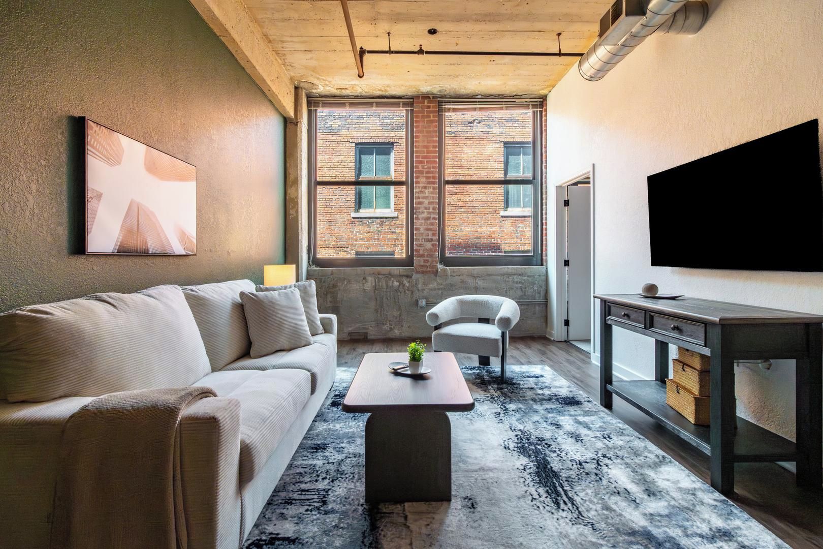 A living room with a sofa, armchair, coffee table, and a television.