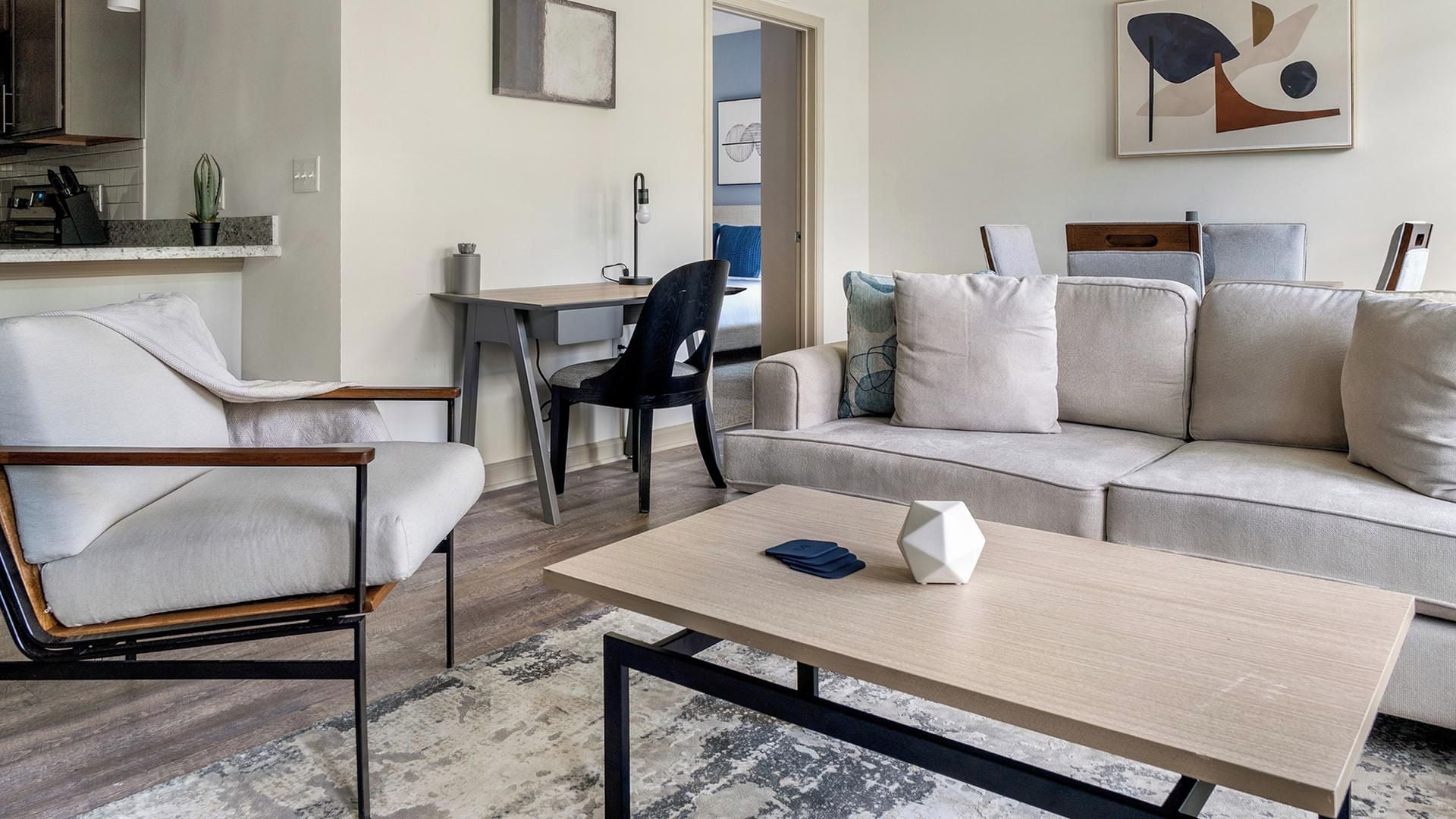A modern living room with a sofa, a chair, a coffee table, and a desk.