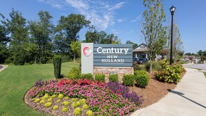 A sign for Century New Holland apartment homes with a landscaped garden in front. - Landing | Incredible 2BD, Gym (Gainesville)