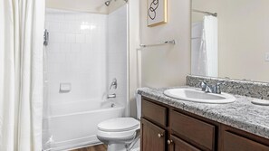Een badkamer met een douche, toilet en wastafel.