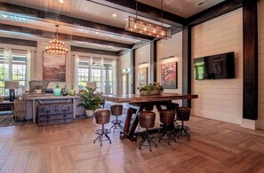 A spacious kitchen with a large island, bar stools, and a dining area with a wooden table.