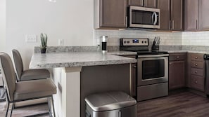 A kitchen with a built-in island, stainless steel appliances, and dark wooden cabinets.