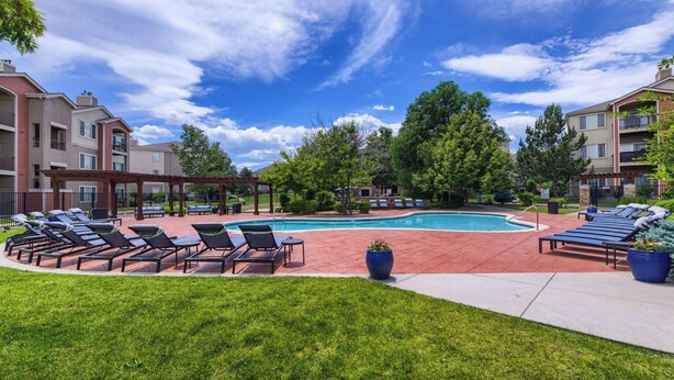 A poolside area with lounge chairs and a swimming pool, surrounded by greenery and multi-story buildings. - Landing | Modern 2BD, Yoga Studio, Pool (Lakewood)