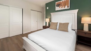 A bedroom with a large bed, two nightstands, a wall-mounted lamp, and a door. - Landing | Amazing 1BD in Kannapolis (Kannapolis)