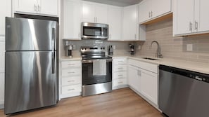 A modern kitchen with stainless steel appliances, white cabinetry, and a tiled backsplash. - Landing | Amazing 1BD in Kannapolis (Kannapolis)