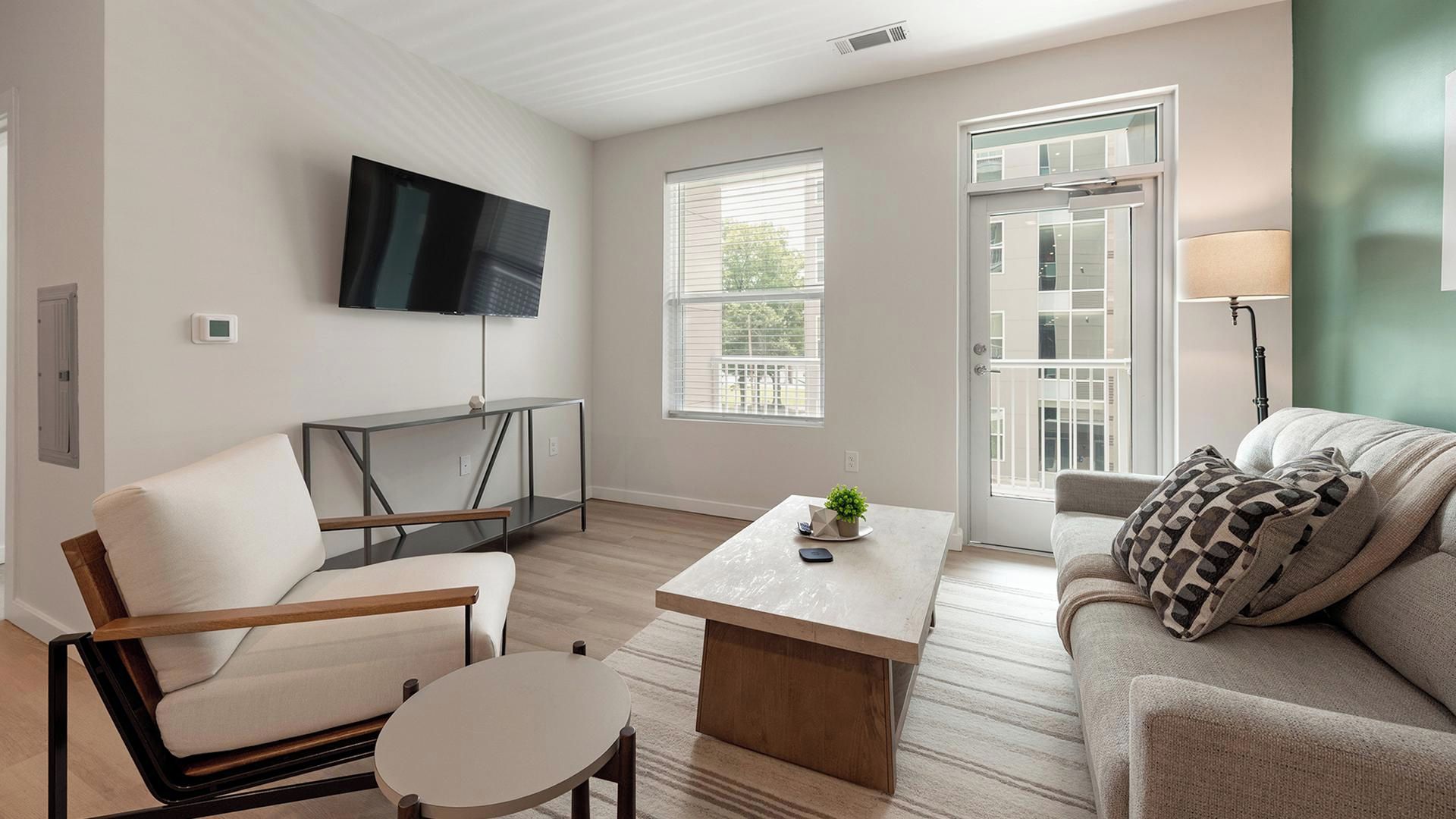 Uma sala de estar moderna com televisão de tela plana, um sofá, uma mesa de centro e um espaço para refeições.