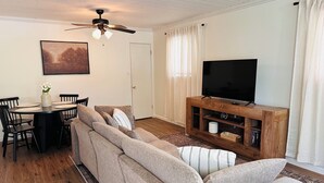 A living room with a sofa, television, and a dining area with chairs and a table.