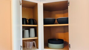 A kitchen cabinet with shelves containing various kitchenware.