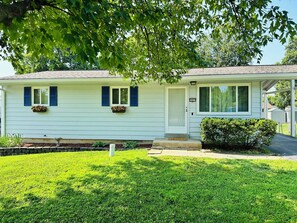 A single-story house with a front porch, a mailbox, and a small garden area.