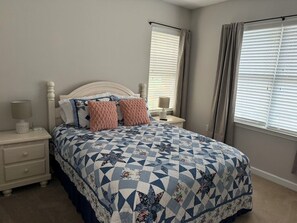 A bedroom with a bed, nightstands, a lamp, and a window with curtains. - 3-bedroom condo in beautiful Calabash golf course community (Calabash)