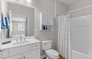 A bathroom with a white sink, toilet, and shower curtain. - 3-bedroom condo in beautiful Calabash golf course community (Calabash)