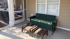 A wooden bench and a table on a porch with a window and a door. - 3-bedroom condo in beautiful Calabash golf course community (Calabash)