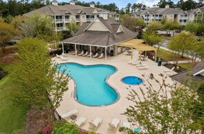 A residential complex with a swimming pool, lounge chairs, and a covered patio area. - 3-bedroom condo in beautiful Calabash golf course community (Calabash)