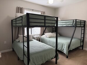 Una camera con letto a castello, una scrivania e una finestra con tende.