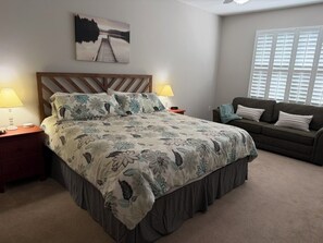 A bedroom with a bed, nightstands, a sofa, and a window with blinds. - 3-bedroom condo in beautiful Calabash golf course community (Calabash)