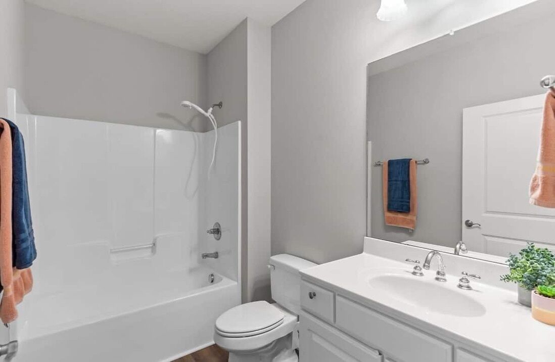 A modern bathroom with a bathtub, toilet, sink, and a large mirror.