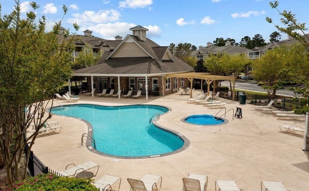 A swimming pool with lounge chairs and a covered seating area.