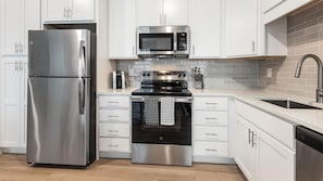 A modern kitchen with stainless steel appliances, white cabinetry, and a tiled backsplash. - Landing | Incredible 1BD in Kannapolis (Kannapolis)